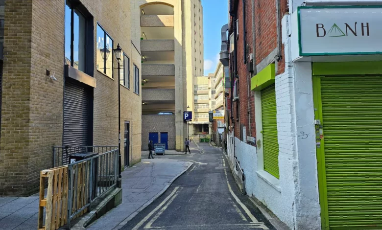 A narrow alley in Croydon overshadowed by a multi-storey car park.