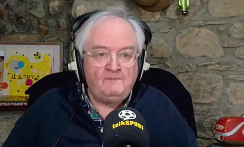 Danny Kelly speaking seriously into a microphone in a radio studio.