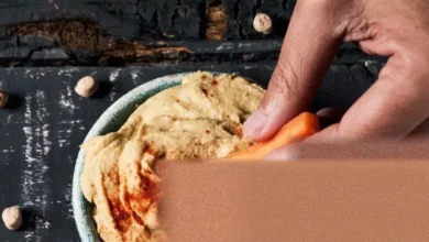 A selection of supermarket hummus tubs in various flavours on a shelf.
