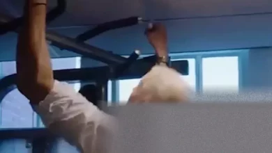 Al Carns MP performing pull-ups in a fire station challenge with a firefighter.