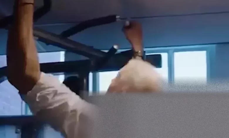 Al Carns MP performing pull-ups in a fire station challenge with a firefighter.