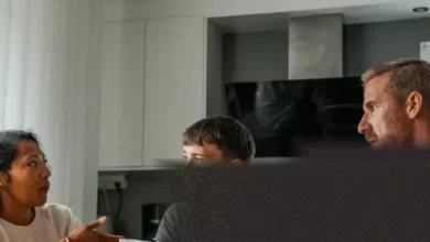 Parents and a young adult discussing finances over a kitchen table.