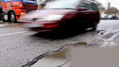 A long stretch of pothole-riddled tarmac on a country road.