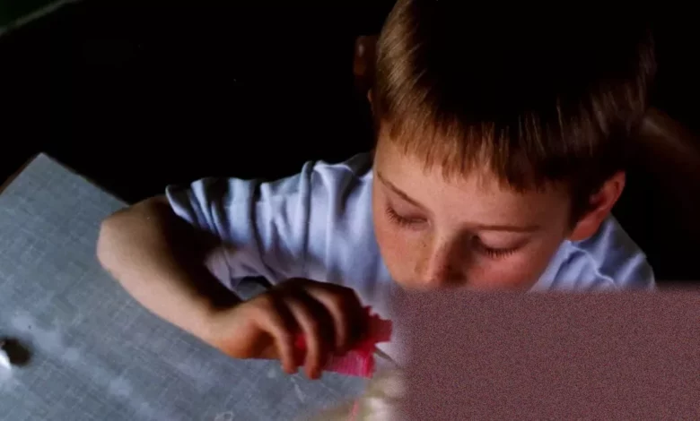 A child arranging dolls in a play scenario on a living room carpet.