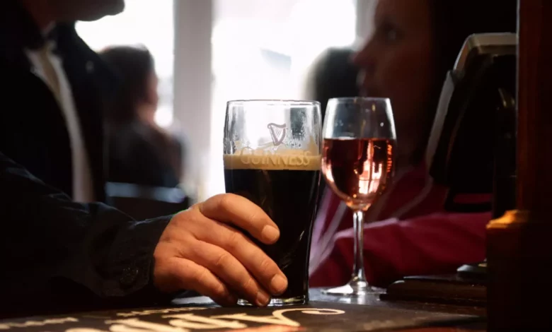 A glass of red wine next to a bowl of grapes on a dining table.