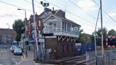 The red brick Victorian signal box beside a railway station and level crossing.