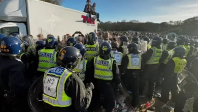 Police officers in riot gear at a rural illegal rave site at night.