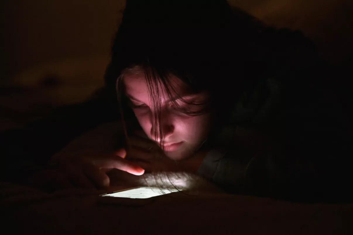 A person using a smartphone displaying an AI nudification app interface
