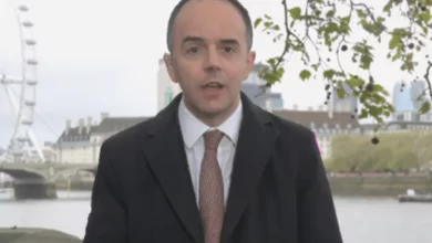 Government minister at a lectern addressing a press conference.