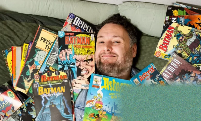 Person reading a comic book in bed at night, phone on bedside table