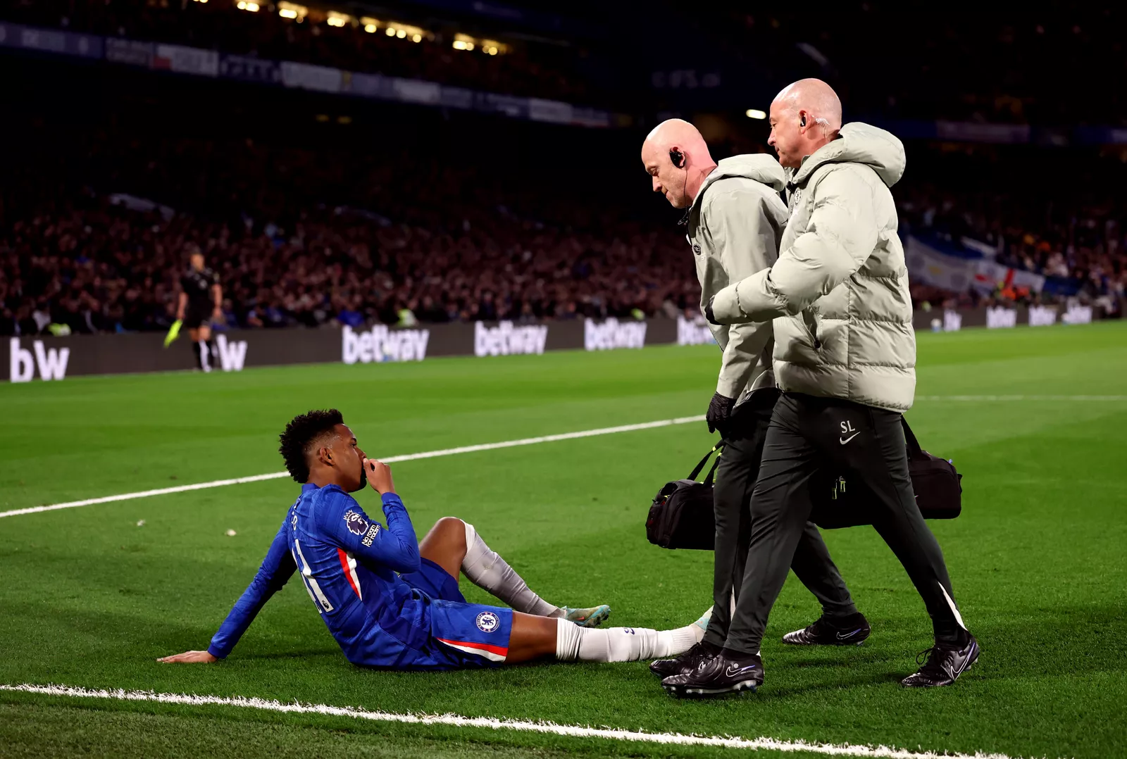 A footballer receiving treatment on the pitch for a thigh injury.