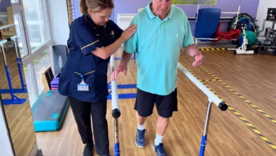 A physiotherapist assisting a patient with stroke rehabilitation exercises in a clinical setting.
