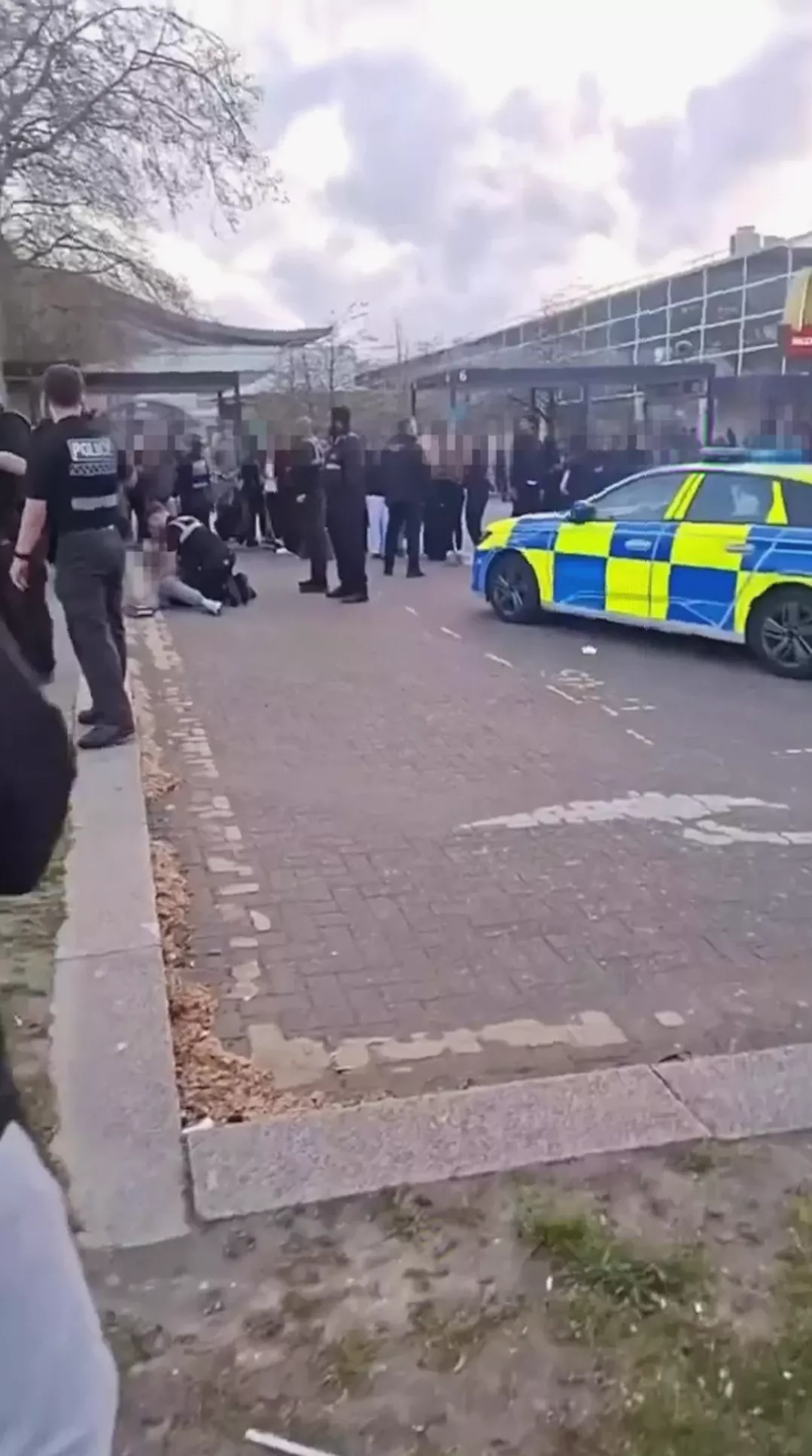 A police vehicle surrounded by teenagers during disorder in a town centre.