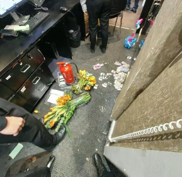 Broken vases and a computer screen scattered across a hotel floor.