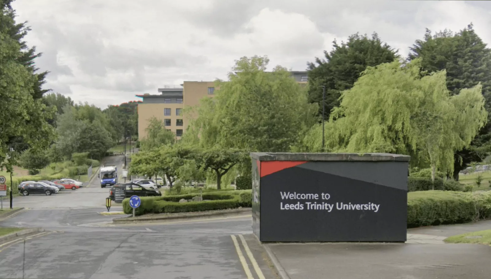 Exterior view of a modern UK university building with students walking outside.