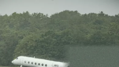 Passengers in full protective disembarking a plane on a tarmac at an airfield.