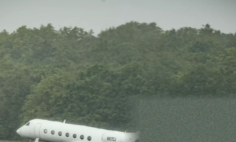 Passengers in full protective disembarking a plane on a tarmac at an airfield.