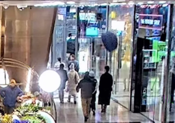 Shoppers on a lower floor reacting in shock as a sofa crashes nearby