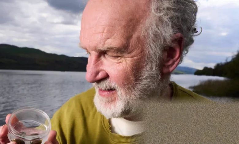 Man holding two tiny glutinous snails in Bala Lake, north Wales