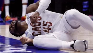 Basketball player lying on court clutching ankle after stepping on photographer's shoe