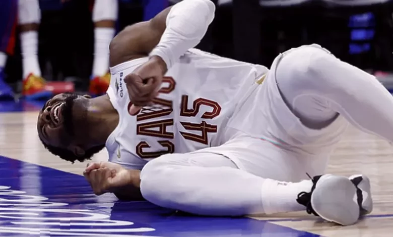 Basketball player lying on court clutching ankle after stepping on photographer's shoe