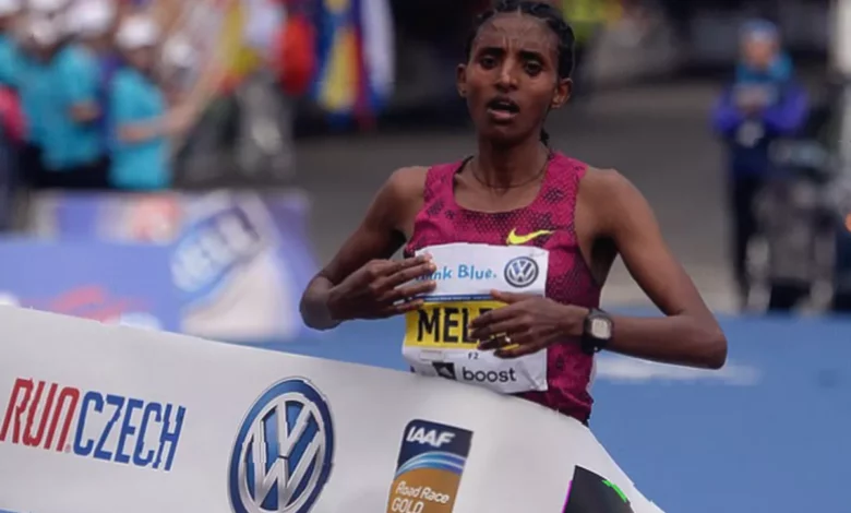 A female marathon runner in a race bib collapses on a sunlit outdoor track in Addis Ababa during a training session.