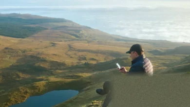Person holding a smartphone with no signal bars while standing on a rural footpath