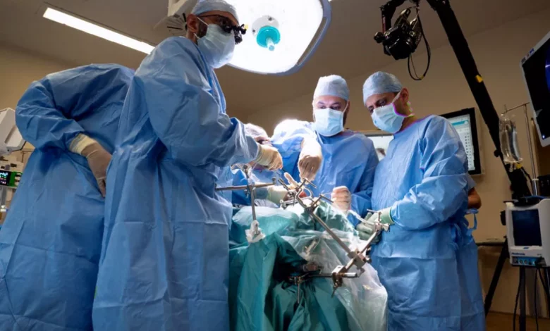 Surgeon consulting a 3D-printed model of a patient's skull and eye socket before surgery.