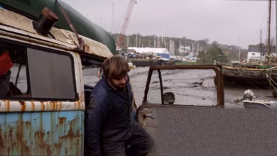 A retired camper van with a crane winches a rotting fibreglass yacht from a muddy Cornish creek.