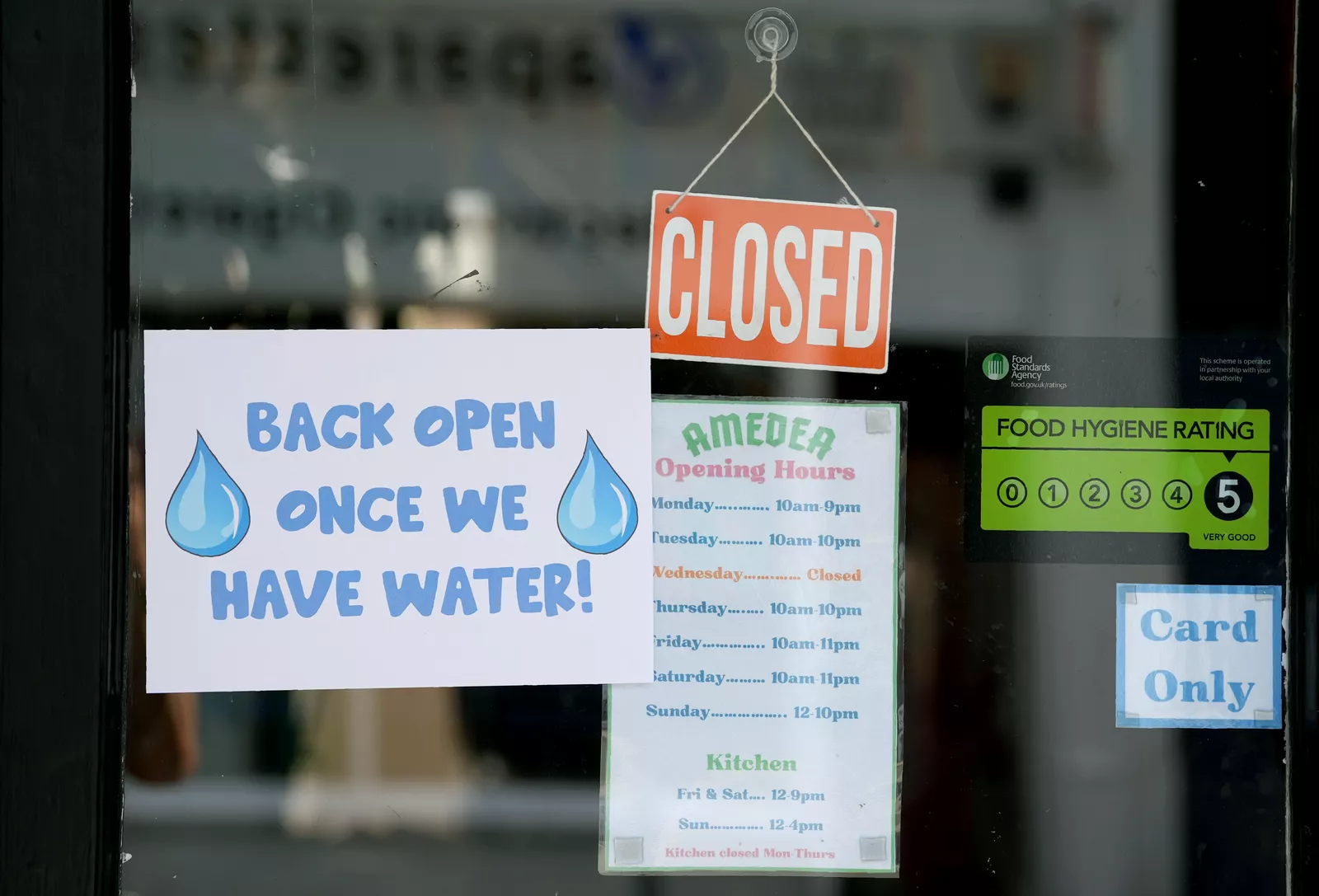Sunbathers sitting near a sign warning against swimming in a lake on a hot day