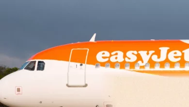 A row of easyJet aircraft parked on a sunlit tarmac at a UK airport