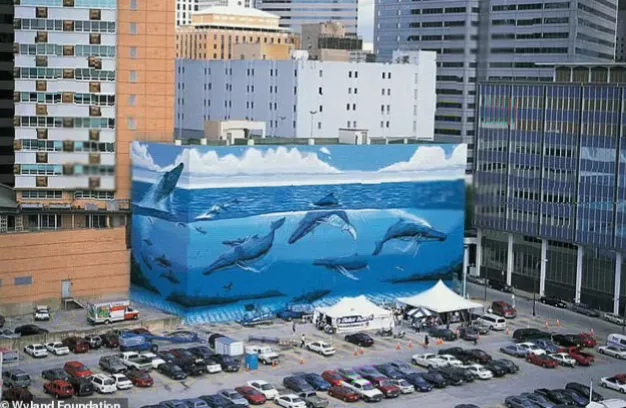 A city street in Dallas with construction barriers near the base of a covered mural