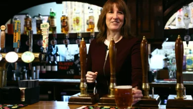 Pub landlord outside a historic inn with a beer garden in the Welsh countryside