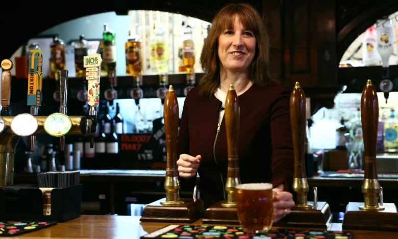 Pub landlord outside a historic inn with a beer garden in the Welsh countryside