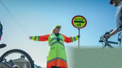 A school crossing patrol officer holding a stop sign on a busy UK road