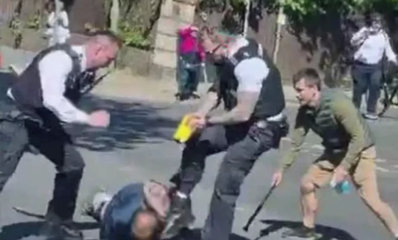 Police officers kick a suspect lying on the ground during an arrest in Golders Green