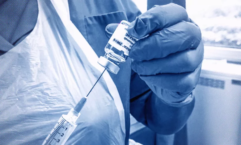 A cancer nurse in a hospital ward wearing a plastic apron and gloves while handling chemotherapy drugs