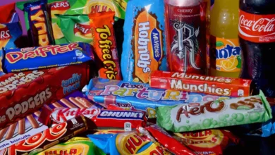 A parent and child shopping in a supermarket aisle filled with brightly packaged sweets and snacks