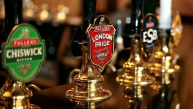 A pint of lager on a bar counter in a London pub with a price tag beside it.