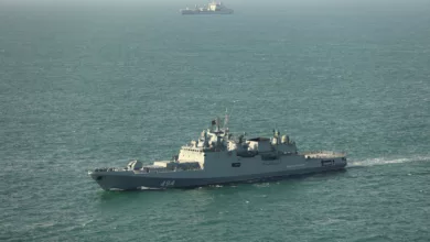 Royal Navy patrol ship sailing alongside a grey Russian frigate in the North Sea