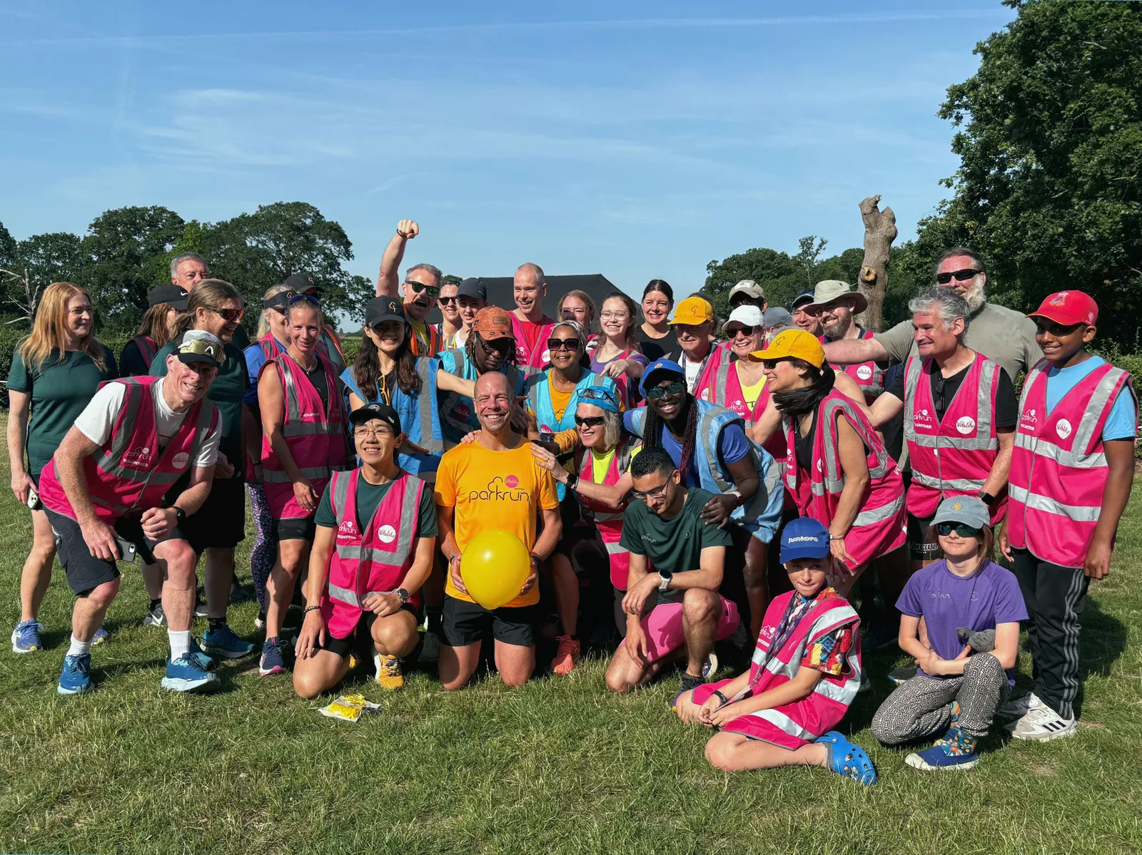 Crowd of supporters holding banners at a parkrun milestone celebration
