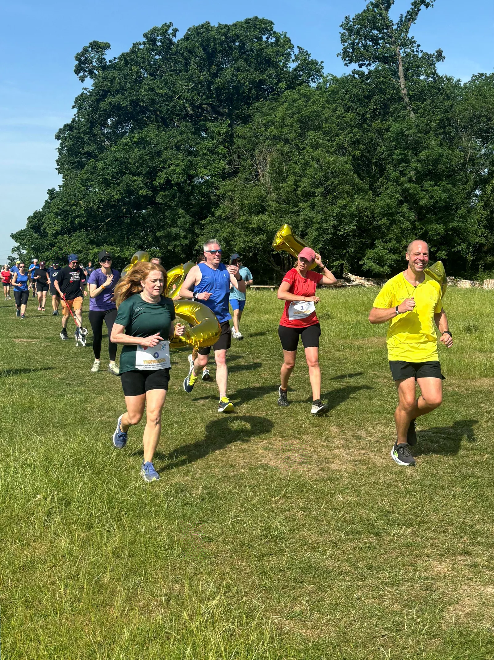 Volunteer handing a yellow 1,000 parkrun T-shirt to a finisher