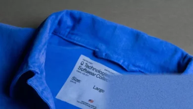 A denim chore coat with a tech company logo on the chest pocket displayed on a mannequin