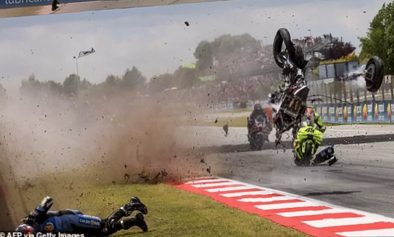 Debris scattered across the racetrack after a high-speed collision between two MotoGP bikes on a straight section.