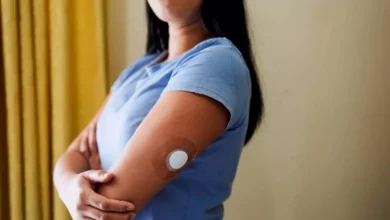 A woman looking at a blood glucose monitor in a UK kitchen