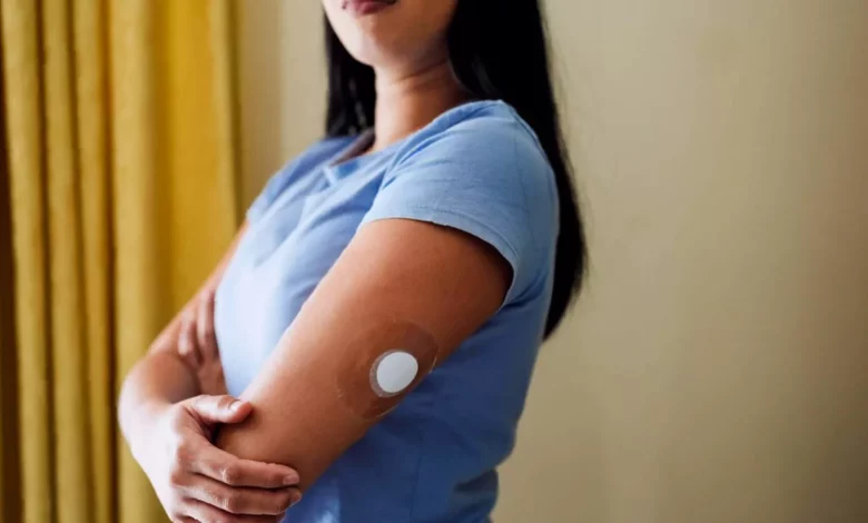 A woman looking at a blood glucose monitor in a UK kitchen