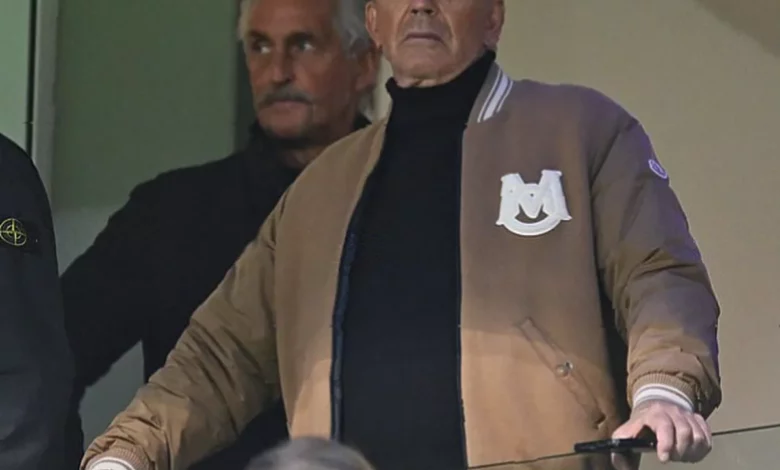 Kevin Costner watching an AFL match from a hospitality box at the Gabba stadium