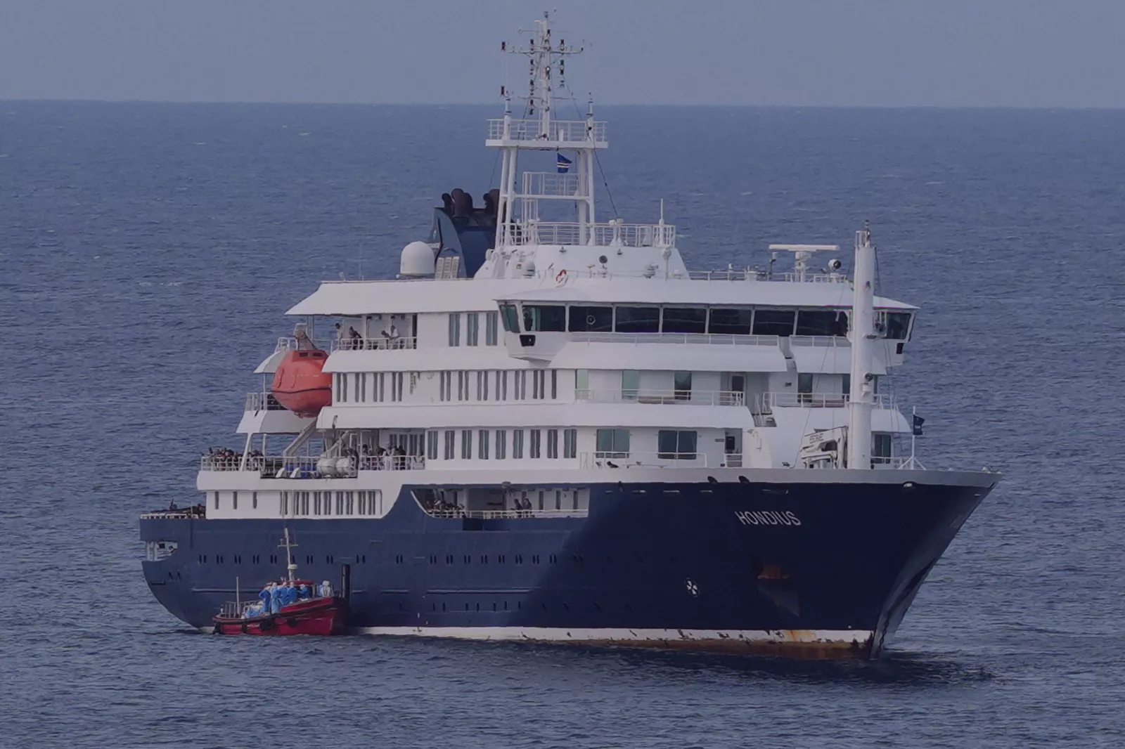 Health workers in protective gear assessing passengers on vessel deck
