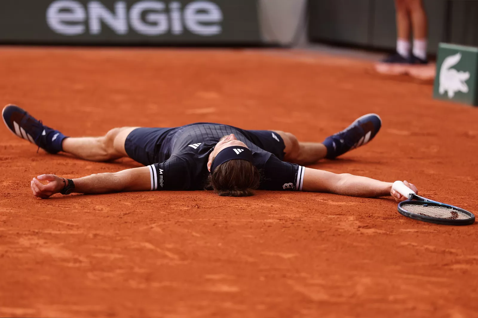 German player collapses onto the clay after match point victory
