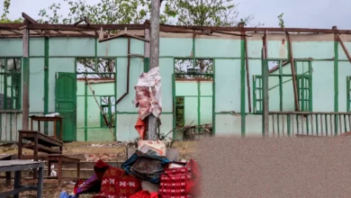 Students walking past a damaged school building in a conflict zone